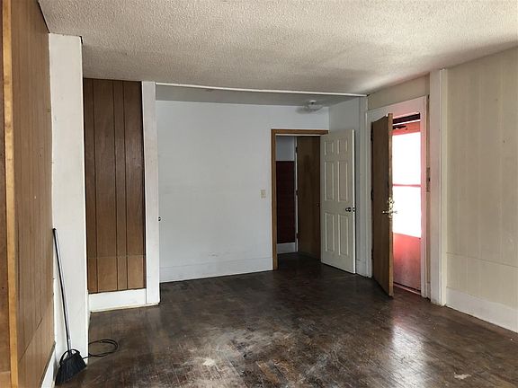 Staircase is behind the far while in this photo.  Large living room with hardwood floors.  There used to be a fireplace on the West wall.