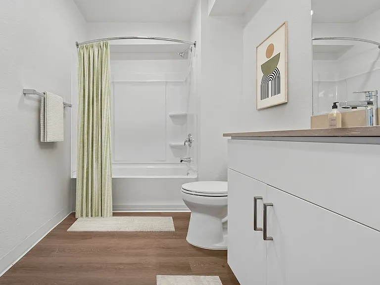 Renovated Package bath with beige quartz countertops, white cabinetry, and hard surface flooring