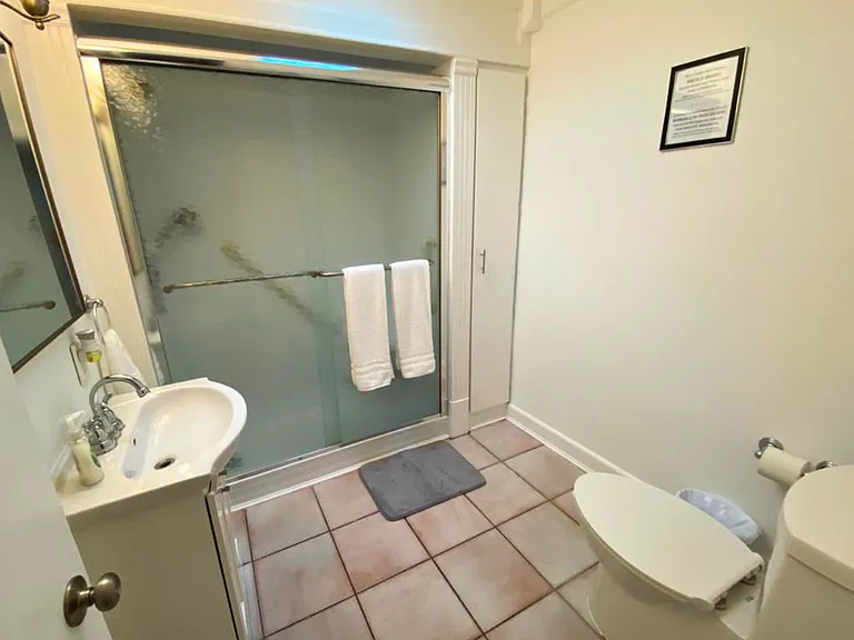 Spotless, fully equipped bathroom with vanity, toilet & glass-enclosed shower.