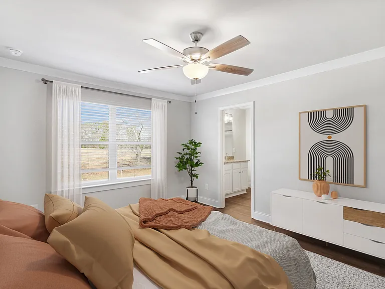 Another view of the spacious primary suite showcasing a grand bed and modern ceiling fan.