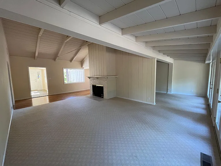 Bright, airy living room features high vaulted ceiling, two wood burning fireplaces, plush carpeting and floor-to-ceiling glass panels and patio doors that flows to a relaxing backyard with a trellis patio cover surrounded by mature trees.