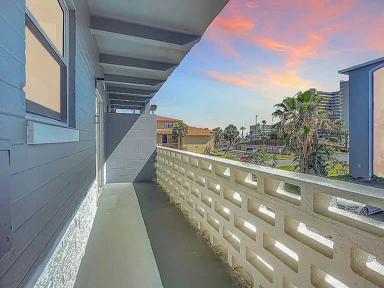 Charming balcony view with vibrant sunset sky and palm trees, offering a serene outdoor retreat.