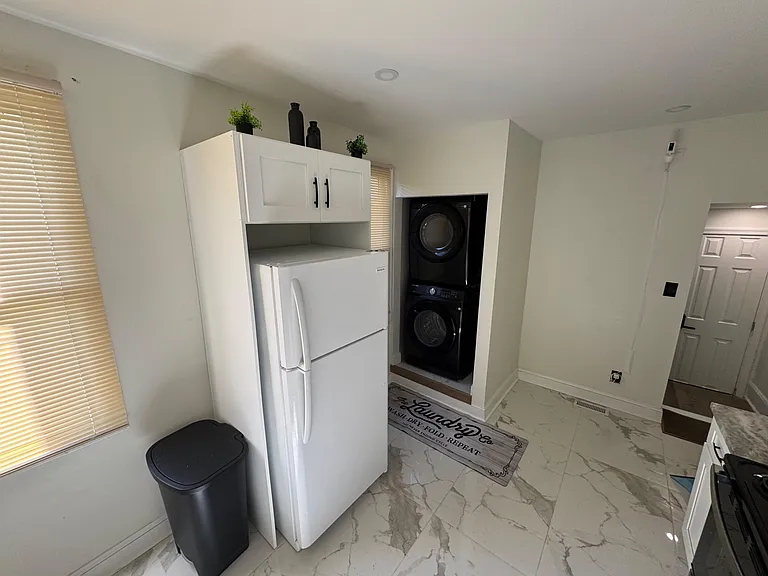Dedicated laundry nook with stacked washer/dryer, overhead storage, and adjacent utility space for daily convenience.