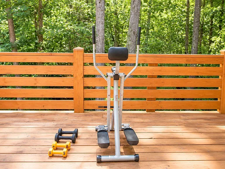 Private outdoor deck with wood railing and forest views, offering space for relaxing, fresh air, and light exercise.