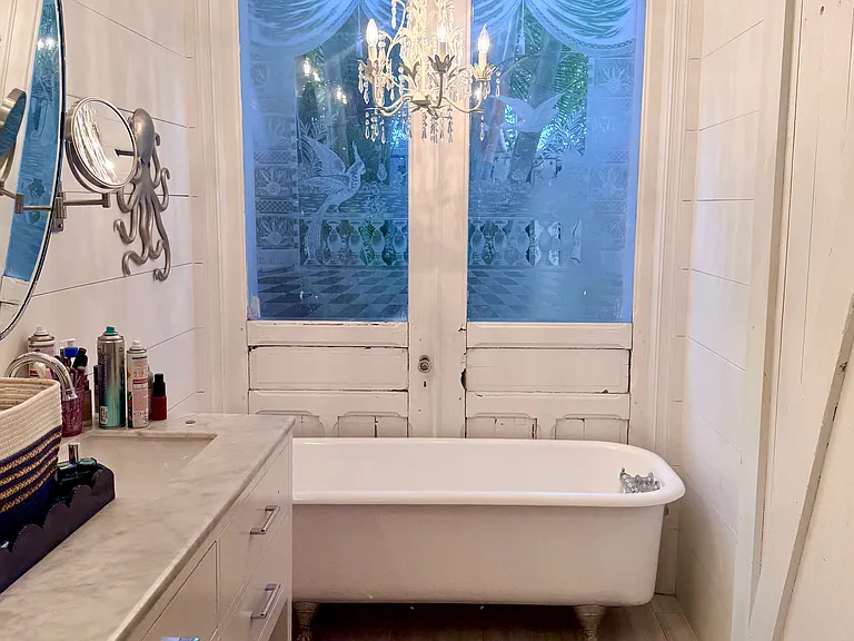 Antique glass doors with clawfoot tub in master bedroom and barn door