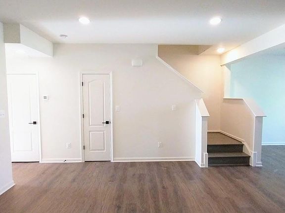 from living room, view of 1/2 bathroom door (left), under-stairs storage, and oak finished staircase to the second level