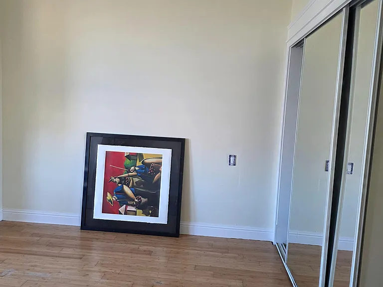 Unfurnished bedroom with wood-look flooring, neutral walls, and mirrored sliding closet doors for convenient storage.