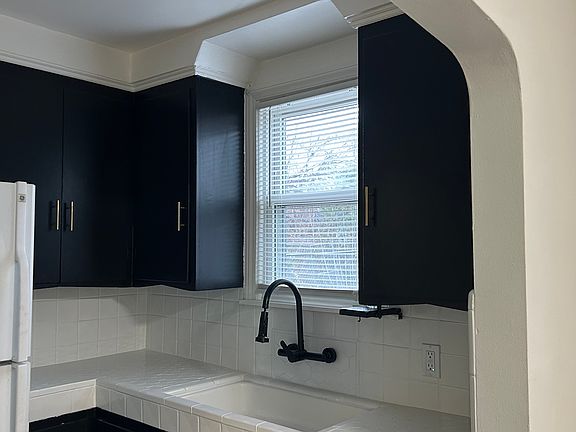 Updated kitchen featuring modern cabinetry, tile backsplash, and matte black fixtures