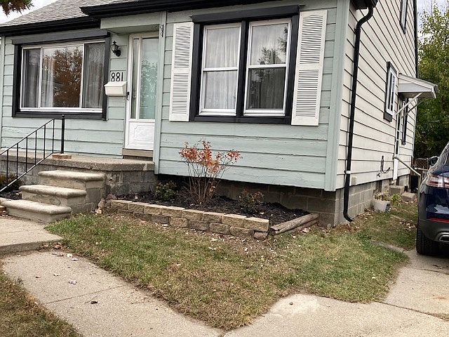 Front of house, driveway side, with perennials and covered entryway offers protection from the elements and provides light for nighttime entrance.