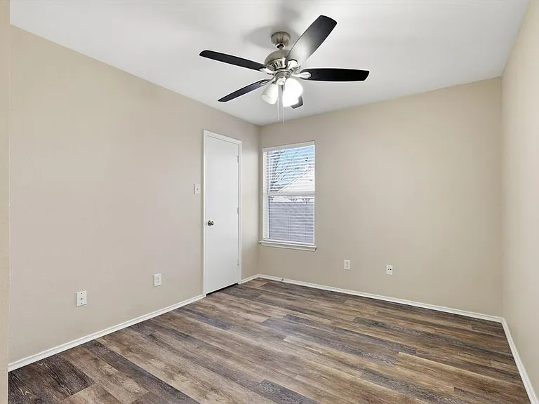 Empty room with dark wood-type flooring and a ceiling fan