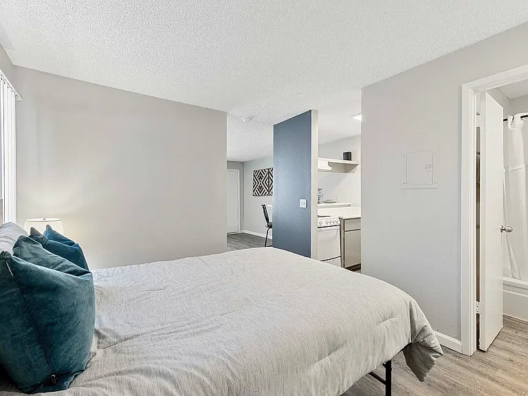 Experience modern comfort in this cozy bedroom with seamless access to the kitchen.