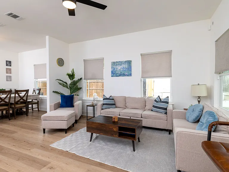 Relax in this bright, open-concept living room featuring a spacious L-shaped sectional ideal for group lounging or family movie nights.