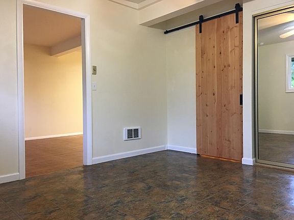 The East Room. There is an overhead fan for circulation, and a thermostat controlled electric wall heater for warmth. The doorway to the west room is on the left. The barn door leads to the bath and laundry. The edge of the closet is on the right.