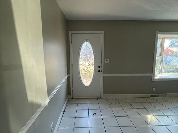 Living Room with decorative front door and tile flooring. Freshly painted walls and trim.