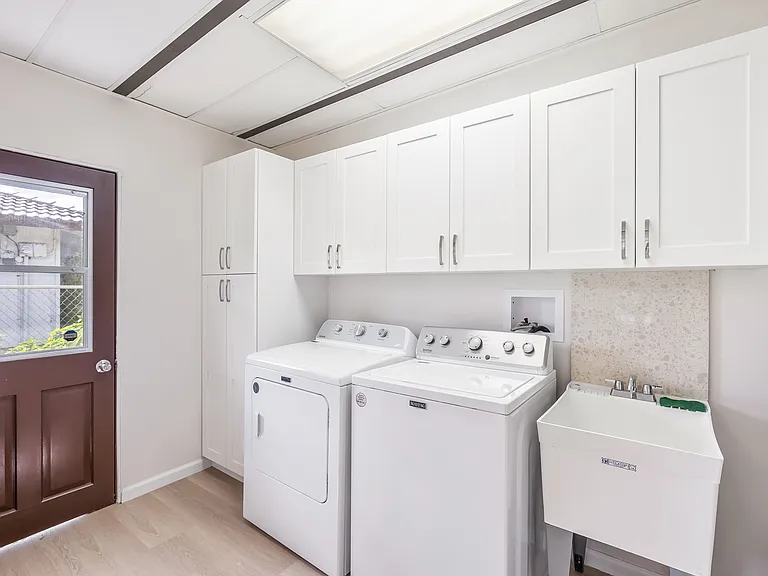 Indoor laundry room with utility sink has added storage cabinets.