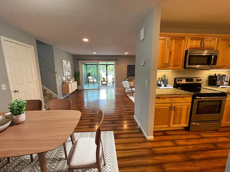 View from the dining room. 3-season patio in the distance, both sets of stairs to the left, and kitchen to the right.