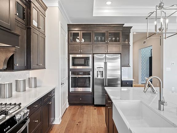 Kitchen with island, pendant lighting and glass-front upper cabinets