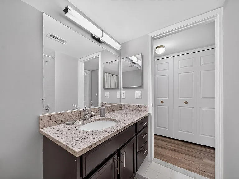 Modern bathroom with large vanity mirror and tub/shower at Lakeside Village Apartments in Clinton Township, MI