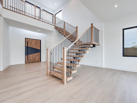 A modern, open-concept interior with a wooden spiral staircase leading to an upper level, surrounded