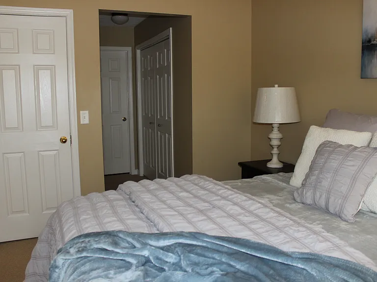Primary bedroom suite with two closets and an attached double sink vanity and garden tub