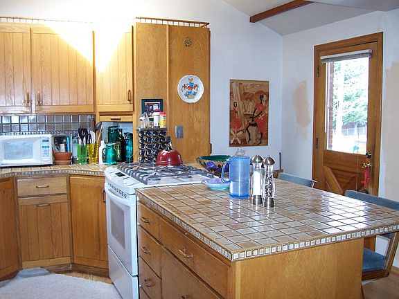 Cook's kitchen with gas range and one of two entrances to home. Upholstered stools or hipper backless black ones available. Other stuff not.