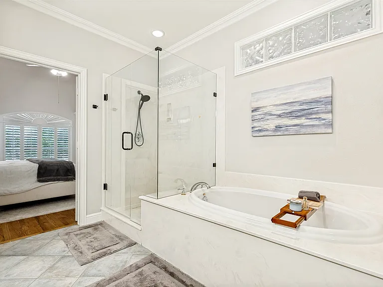 Spacious bathroom featuring a glass-enclosed shower, a built-in soaking tub with surrounding countertop, and tile flooring