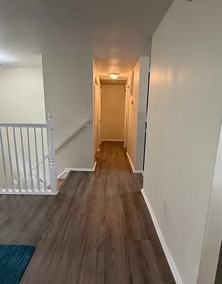 Upstairs hallway with wood-look flooring, stair railing, and easy access to multiple rooms for convenient daily flow.
