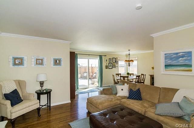 Living room with gleaming hardwood floors, crown moldings opens