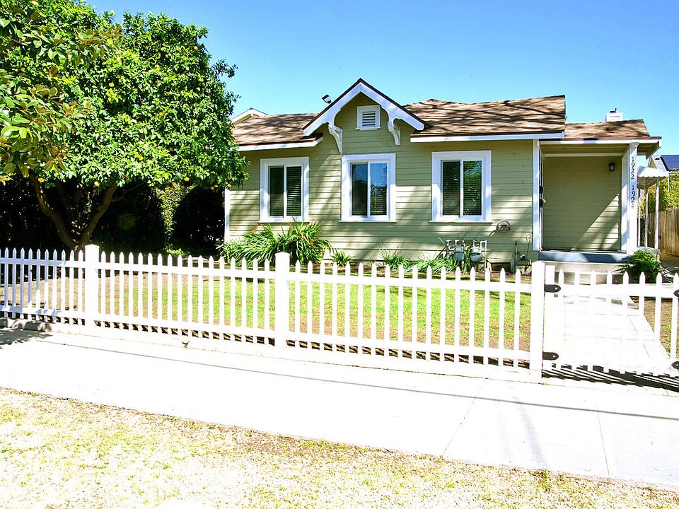 This is the exterior of the property showing the fenced in yard and mature grapefruit tree.
