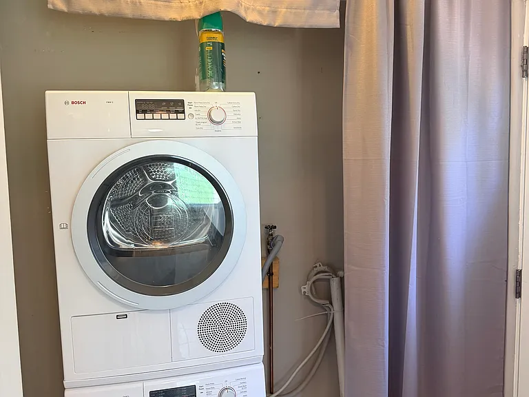 Unit includes recently installed Bosch washer/dryer combo in a clean, neatly organized utility room with shelves for tools and supplies.