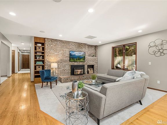 Family room with gas fireplace insert surrounded by floor to ceiling brick wall décor and recessed shelving.