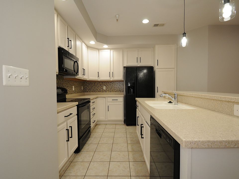 Another angle of the kitchen. Cabinets have been recently painted, Corian countertops, and glass tile backsplash for easy clean-up.