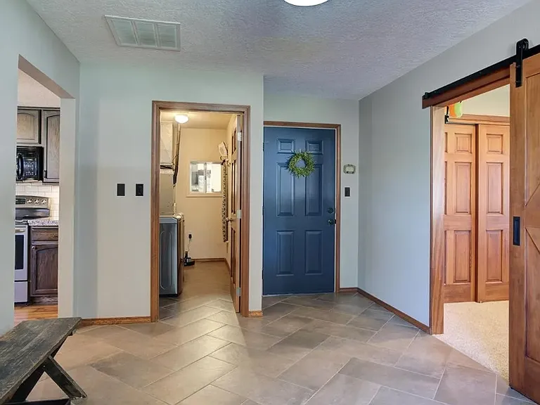 The blue door is the garage entrance where we see an oversized mud room or bonus work from home space. Laundry is next to garage door
