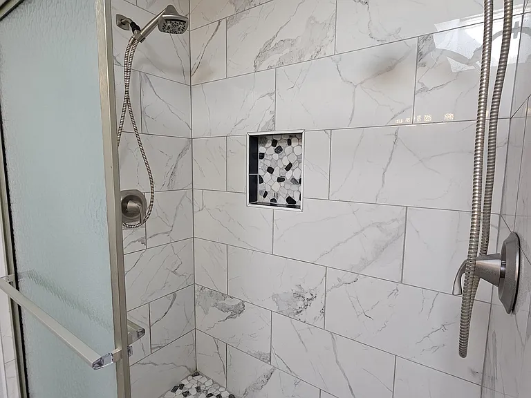 Custom tile in shower featuring dual shower heads.