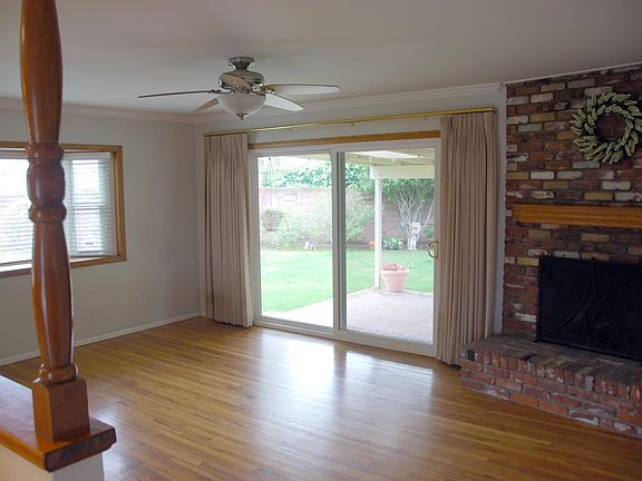 Living Room _ Living room is open and adjacent to dining area and kitchen _ Living room has gas fireplace, bay window and large sliding glass door leading to the back yard _ Smooth ceilings, crown molding, recessed lighting and ceiling fans throughout