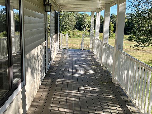 The long front porch, looking toward the stairs. To the left are windows to the master bedroom, the front door, and then windows to the dining area.