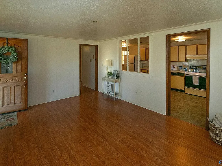 Living room view showing, from left to right, the front door, the hall door, the access to the kitchen.