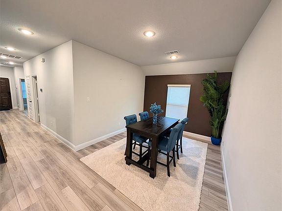 Dining room featuring visible vents, baseboards, a textured ceiling, and light wood-style flooring