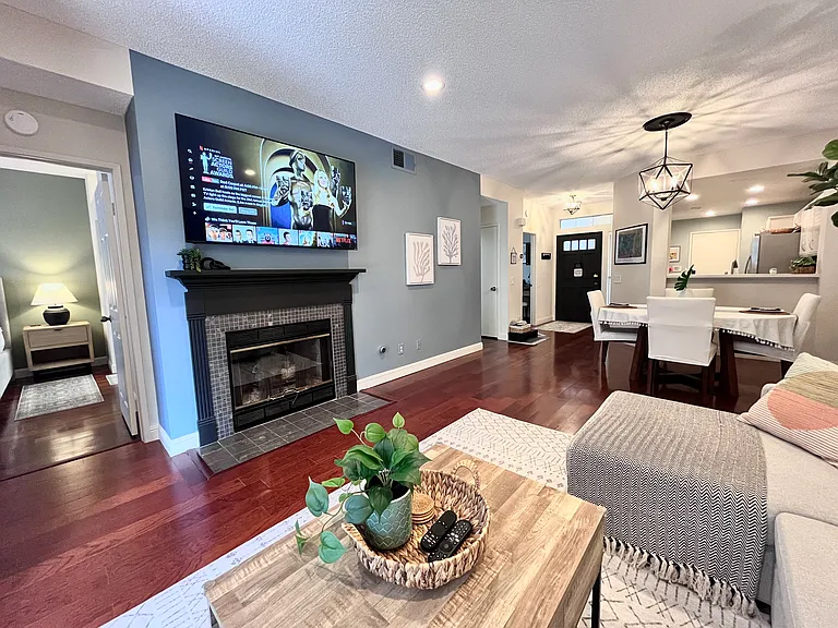 Elegant living and dining room for 4-6 guests with 65" Smart TV and fireplace, flowing into the kitchen and outdoor living area. New Pottery Barn sectional converts to a chaise for cozy movie nights or a king bed for extra guests.