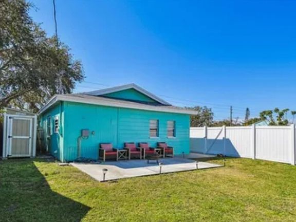 fenced in backyard with a storage shed, outdoor seating and hurricane shutter covers instead of the shed
