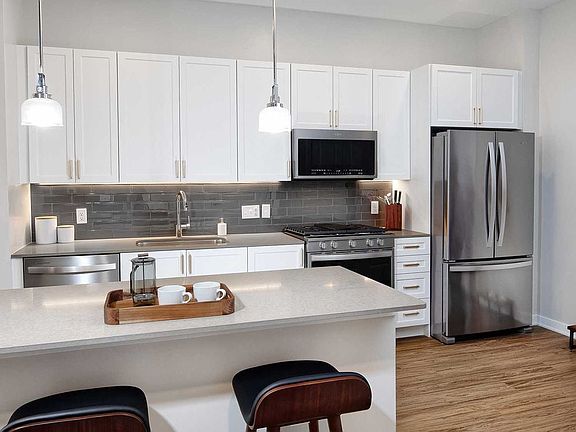 Classic Scheme kitchen with quartz countertops and island, stainless steel appliances, backsplash and hard surface flooring
