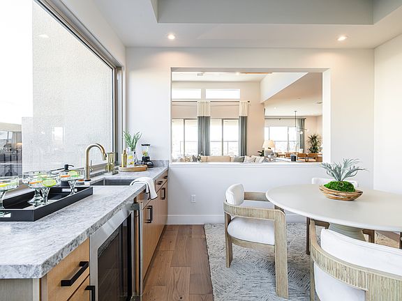 A modern, open-concept kitchen with a marble countertop, wooden cabinets, and a dining area with a r
