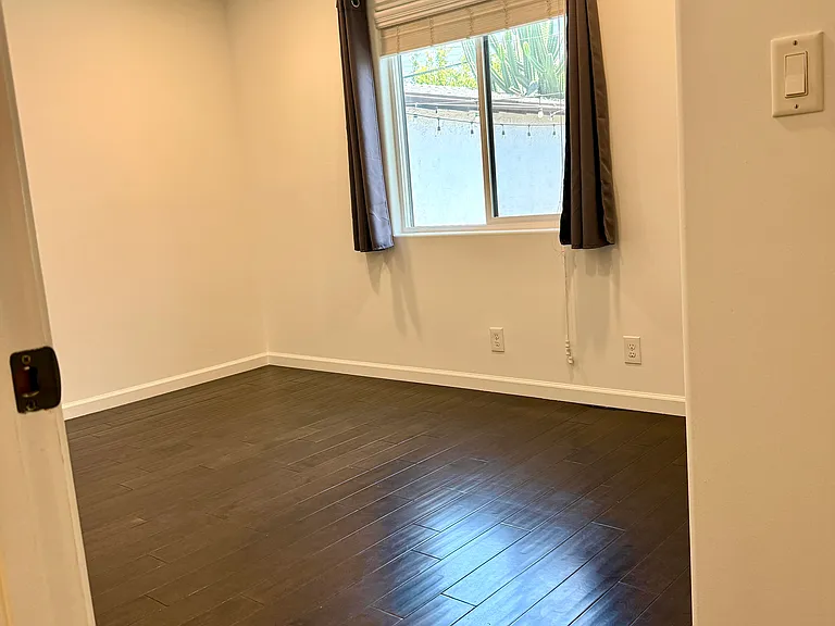 Bedroom 2 with dimmable recessed LED lighting overlooking backyard.