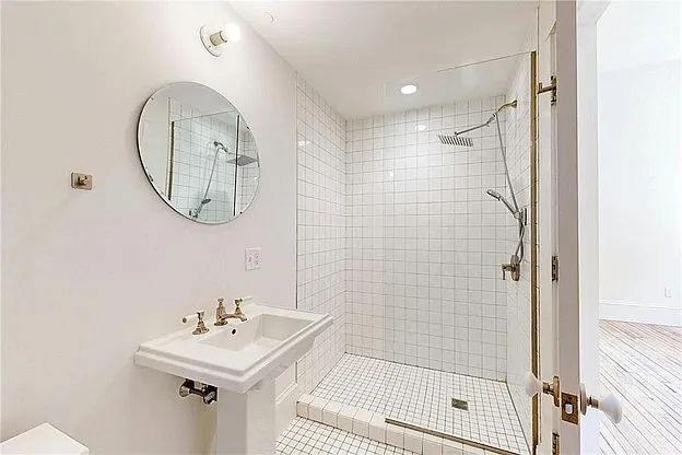 Low curb glass shower with modern rainfall showerhead.