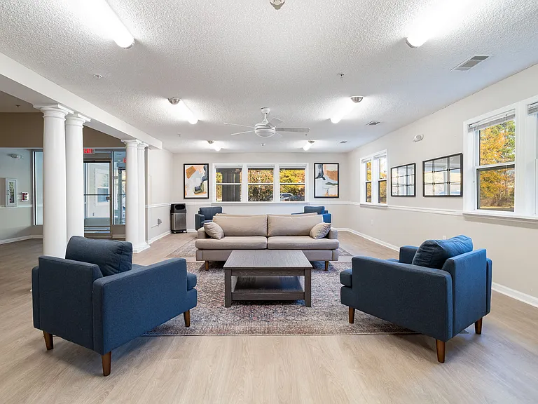 Relax in our inviting community room featuring comfortable seating and abundant natural light from large windows, professionally operated by Highlands Vista Group.