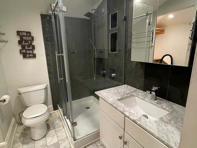 Updated private full bathroom featuring a glass shower, modern vanity, and tile flooring.