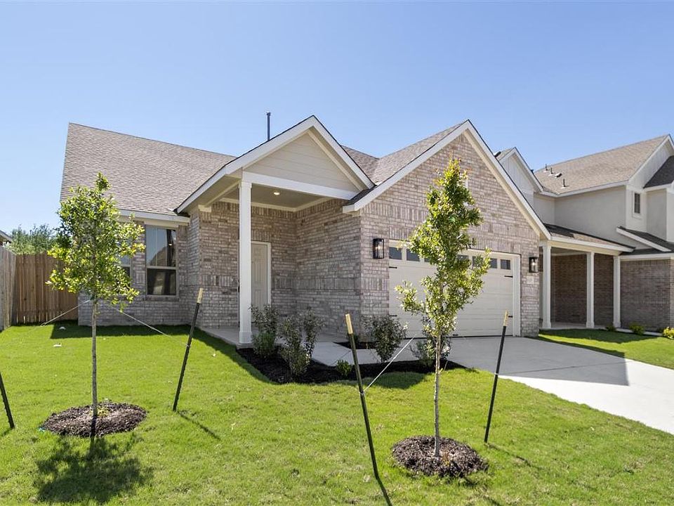 View of front of house featuring driveway, an attached garage, a front yard, brick siding, and fence