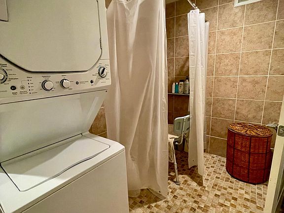 Walk-in ADA accessible shower, entire area tiled. laundry hookups
