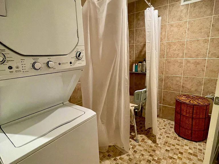 Walk-in ADA accessible shower, entire area tiled. laundry hookups