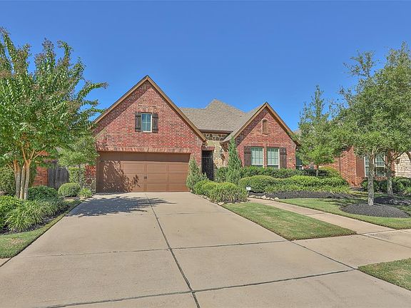 Pretty front elevation with striking symmetrical peaks, stone and brick accents, wood shutters and abundant landscaping.